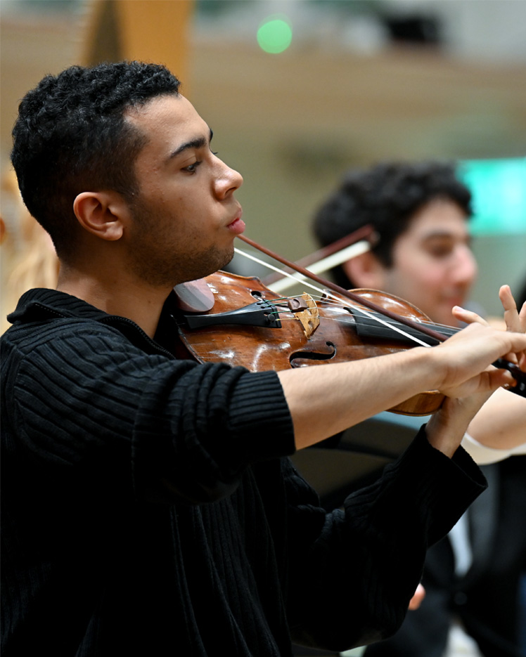 A male violinist playing, wearing a black top.